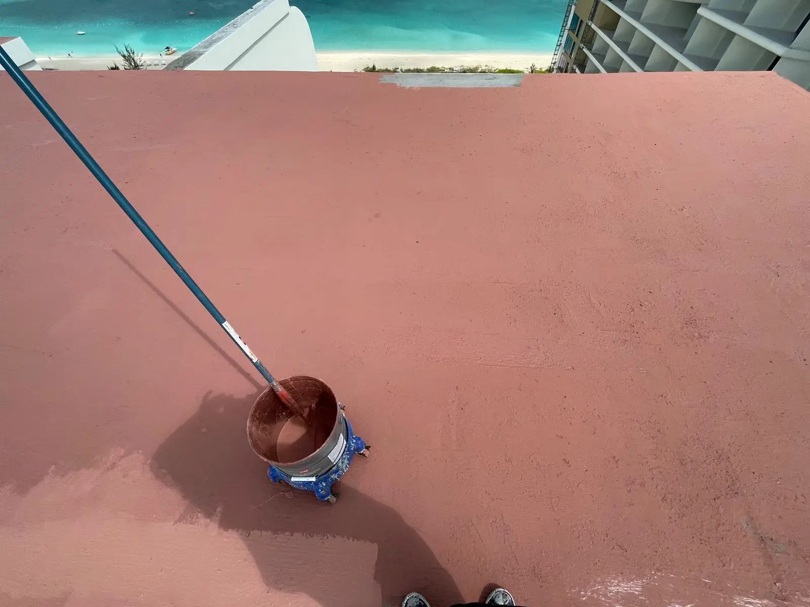 Roller applying the red base coat on the concrete deck, St. Regis, Turks and Caicos