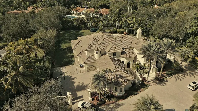 Pinecrest home with a finished tile roof and a palm-lined driveway, aerial view