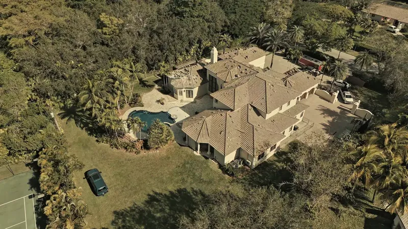 Finished tile roof on a Pinecrest home with a pool and lawn under the tree canopy